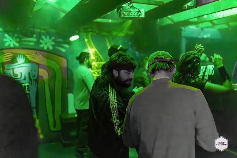 Dancers under the beams beside the painted mural wall. Launch night, May 2025