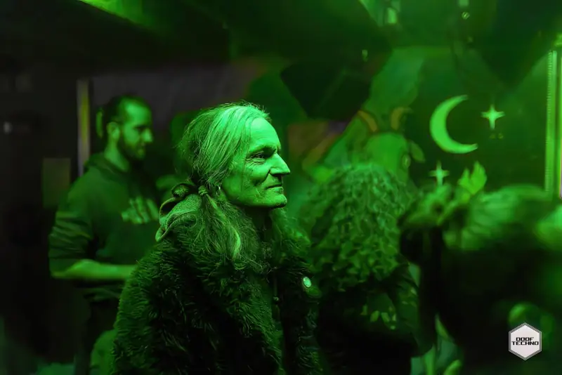 A silver-haired dancer smiles beneath the crescent-moon mural. Launch night, May 2025