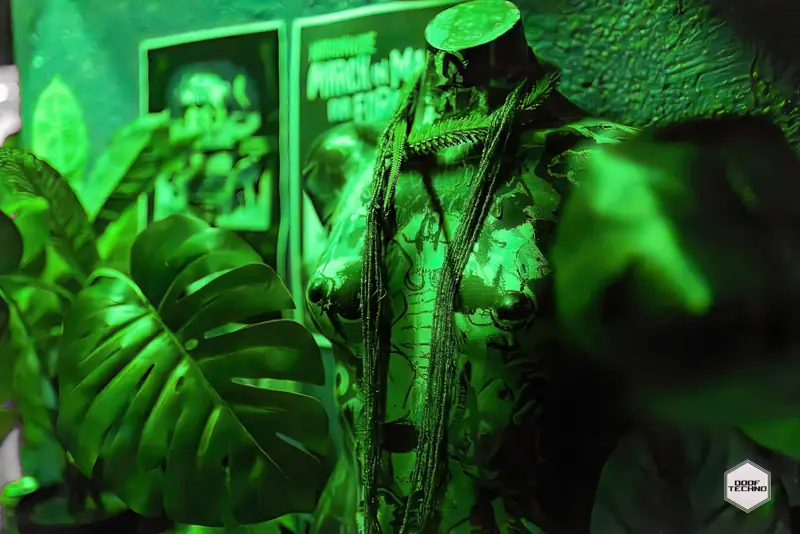 A sculpted torso draped in beads and fern fronds among the monstera leaves. Launch night, May 2025
