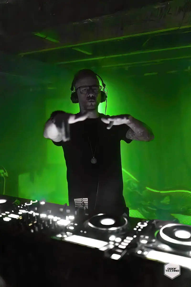 A DJ throws a gesture to the floor from the booth. Launch night, May 2025